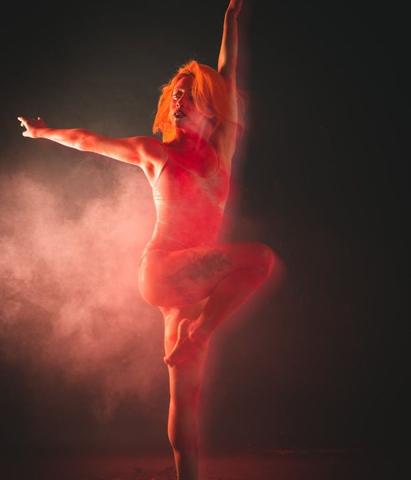 Woman performing a fluid cardio movement in a dark room with mint light trace.
